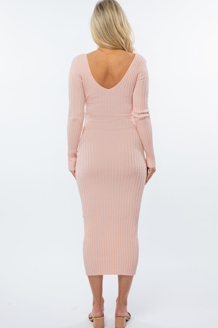 woman wearing a soft pink ribbed maternity dress with a deep v-back and long sleeves, fitted silhouette