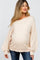 woman wearing a light beige oversized maternity sweater with wide sleeves and a visible baby bump