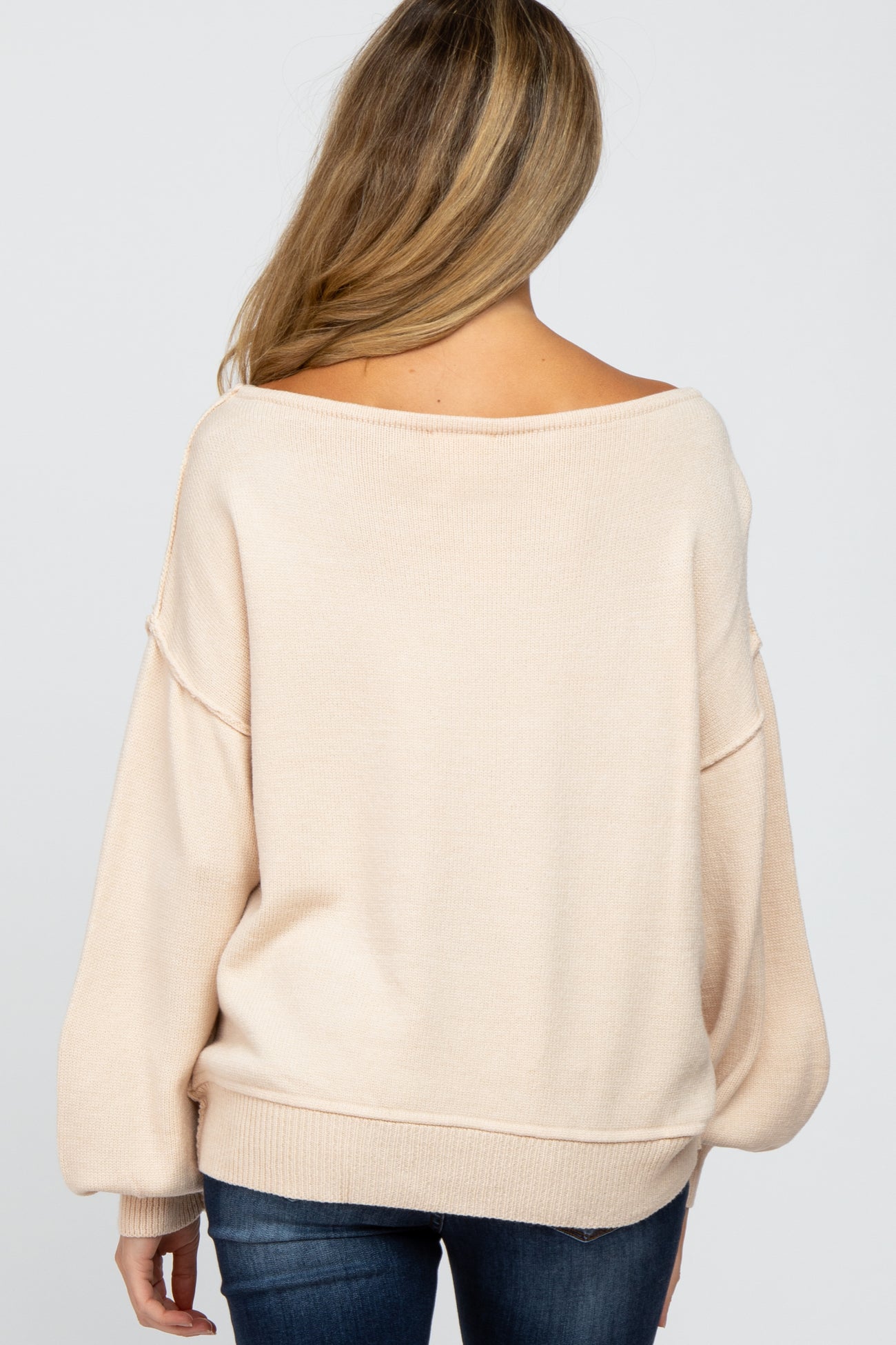 woman wearing a soft beige maternity sweater with a relaxed fit and wide neckline, showing the back view