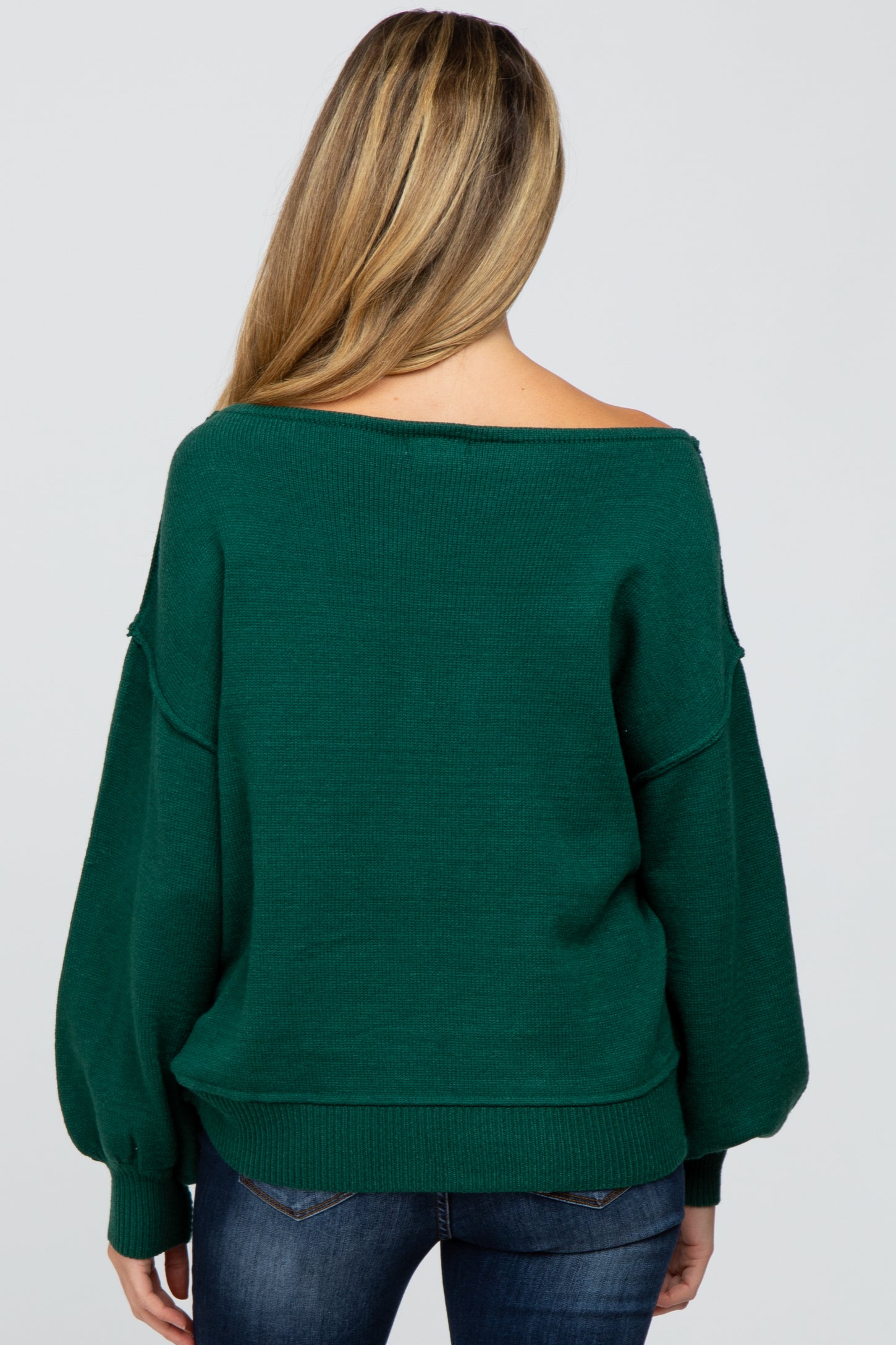 woman wearing a dark green maternity sweater with an off-shoulder design and balloon sleeves, seen from the back