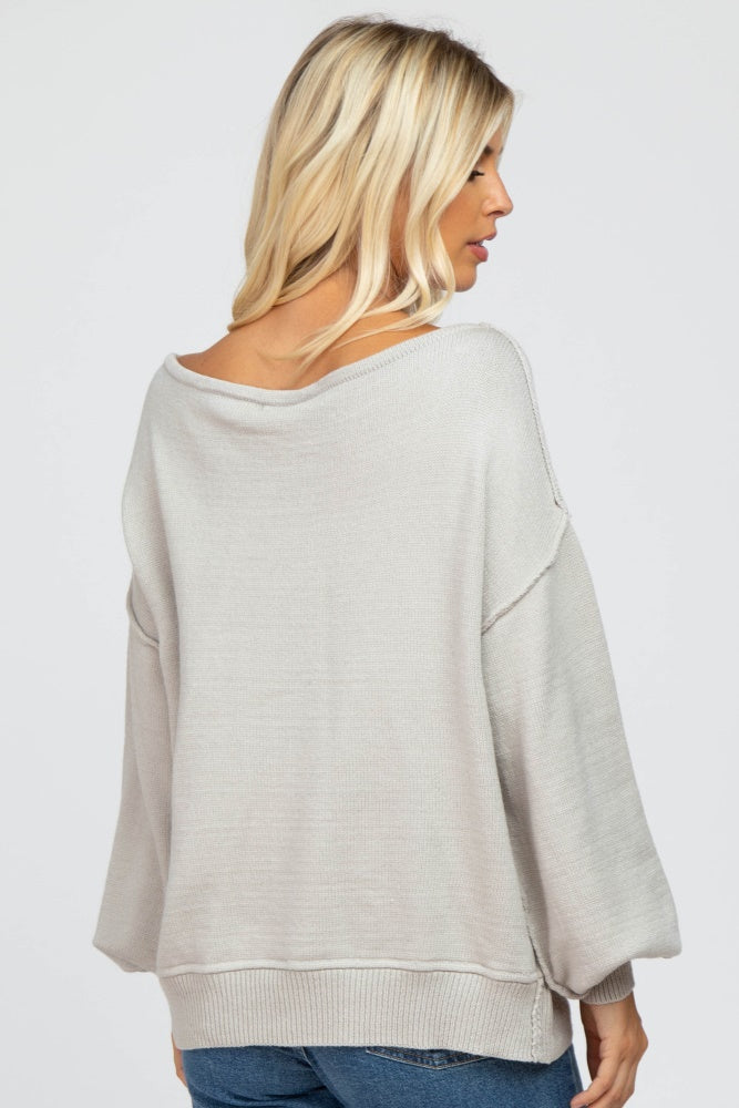 woman wearing a light gray oversized sweater with a wide neck and balloon sleeves, view from the back
