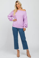 woman wearing a lavender off-shoulder sweater with balloon sleeves and blue cropped jeans, posing confidently