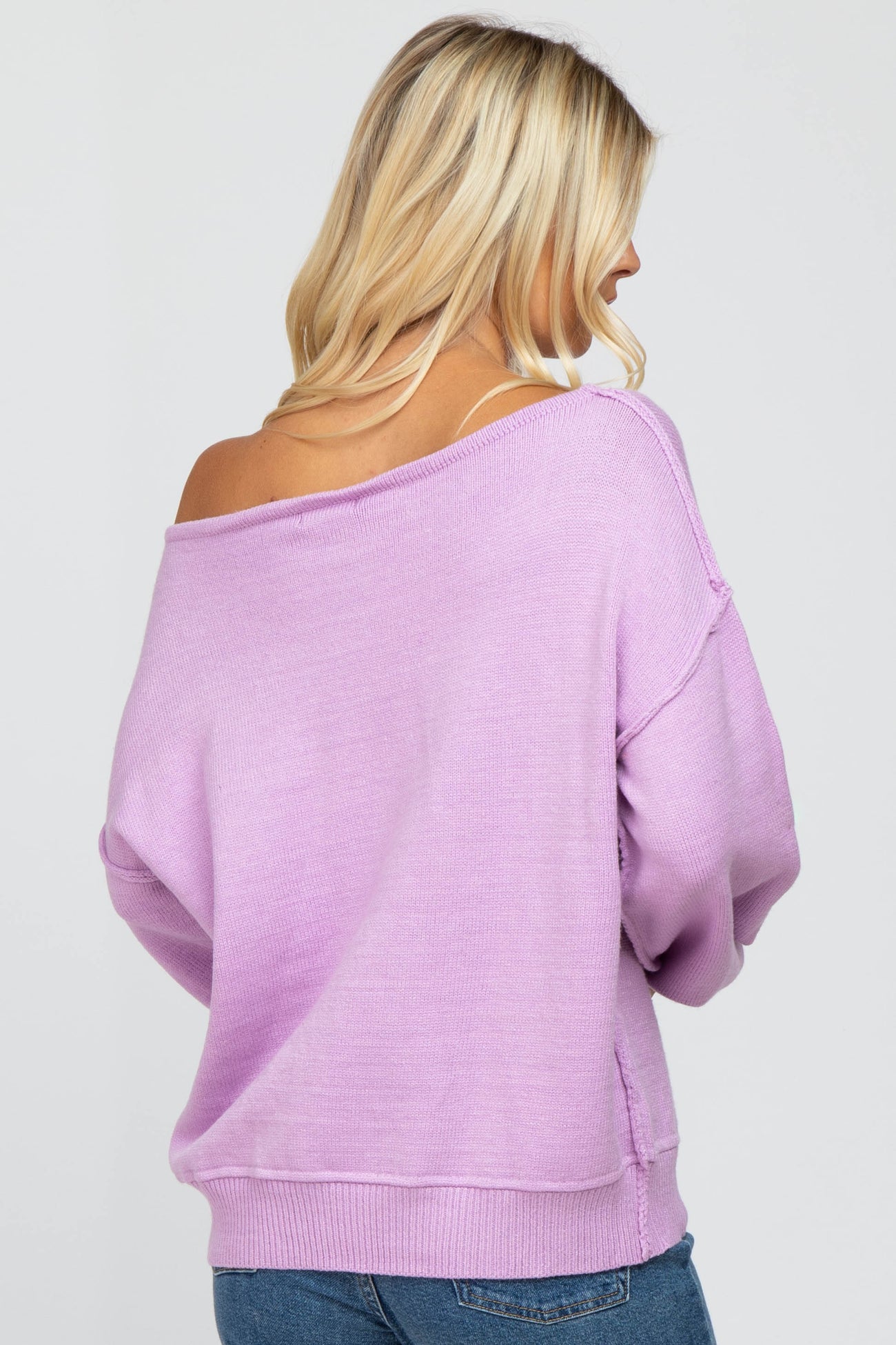 woman wearing a lavender off-the-shoulder sweater with long sleeves and a relaxed fit, seen from the back