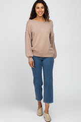 woman wearing a beige oversized sweater and blue cropped jeans with frayed hems