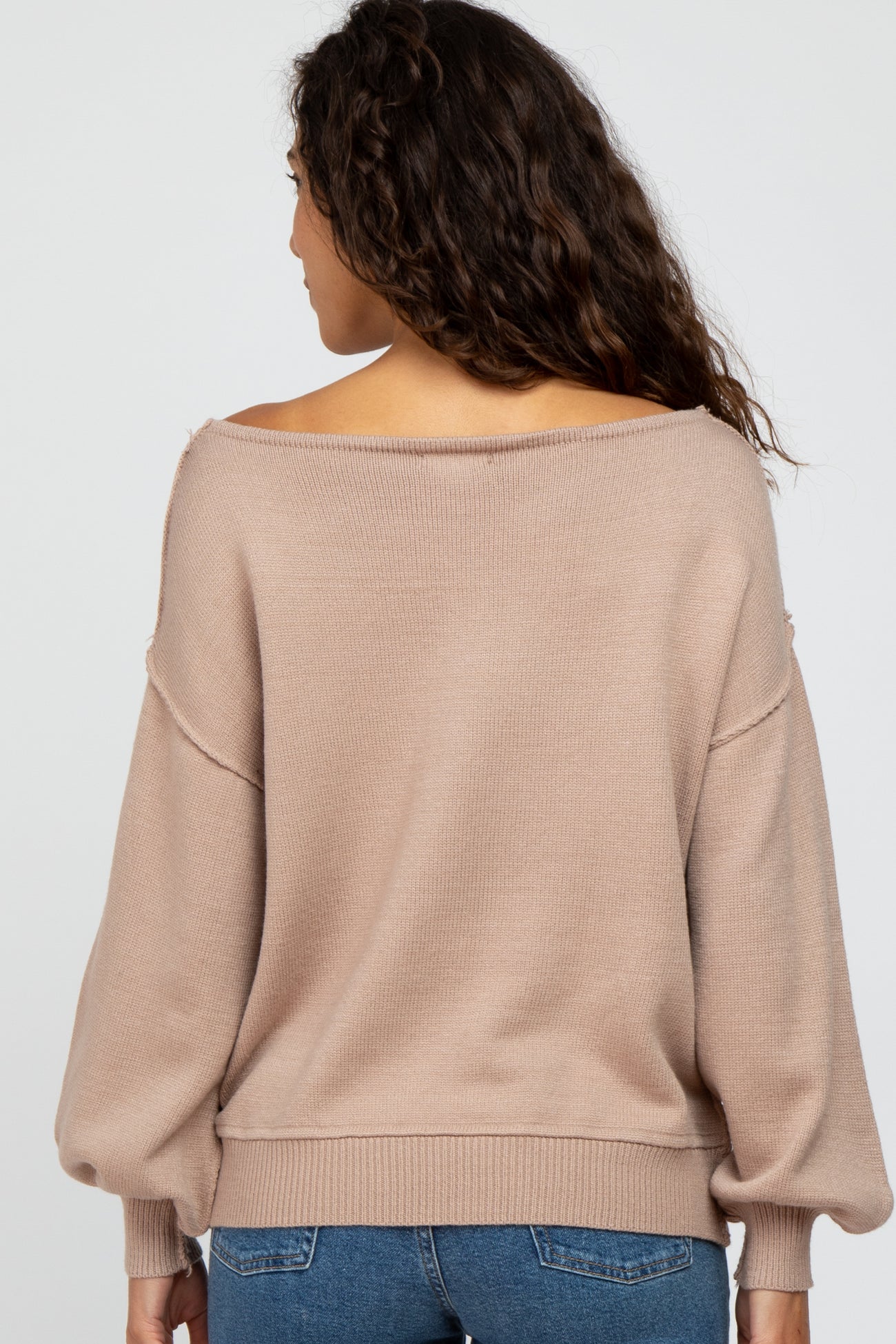 woman wearing a beige off-the-shoulder sweater with balloon sleeves, viewed from the back