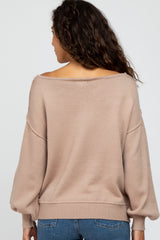 woman wearing a beige off-the-shoulder sweater with balloon sleeves, viewed from the back