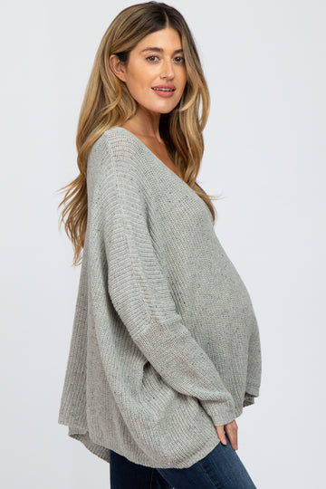 woman wearing a light gray oversized knitted maternity sweater with a visible baby bump