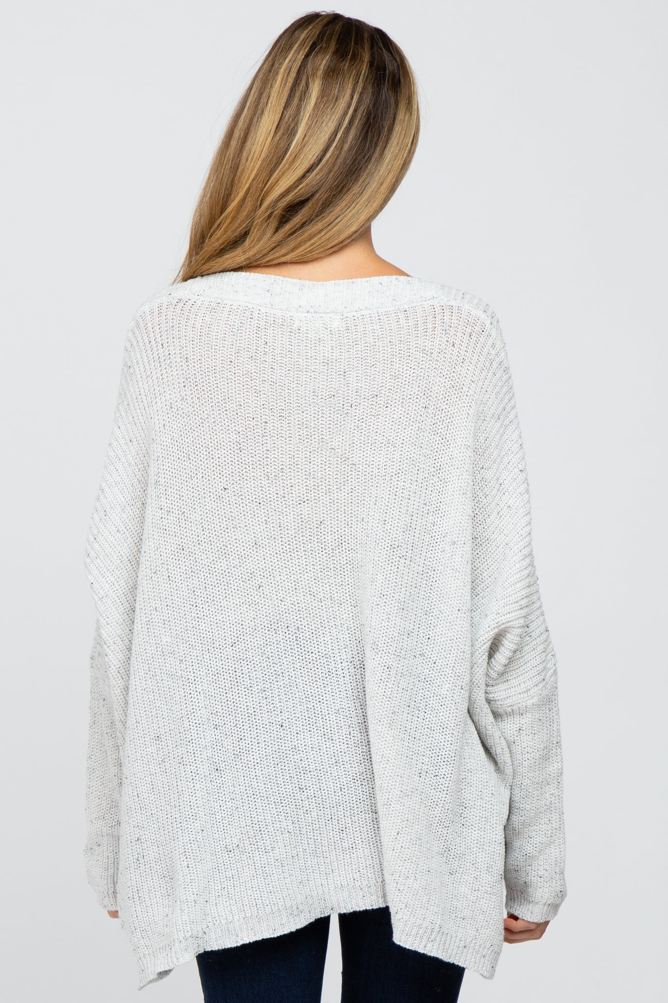 woman wearing a loose-fitting light gray maternity sweater with a relaxed back view
