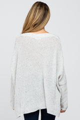 woman wearing a loose-fitting light gray maternity sweater with a relaxed back view
