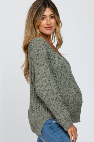 woman wearing a green open knit maternity sweater with a visible baby bump and relaxed fit