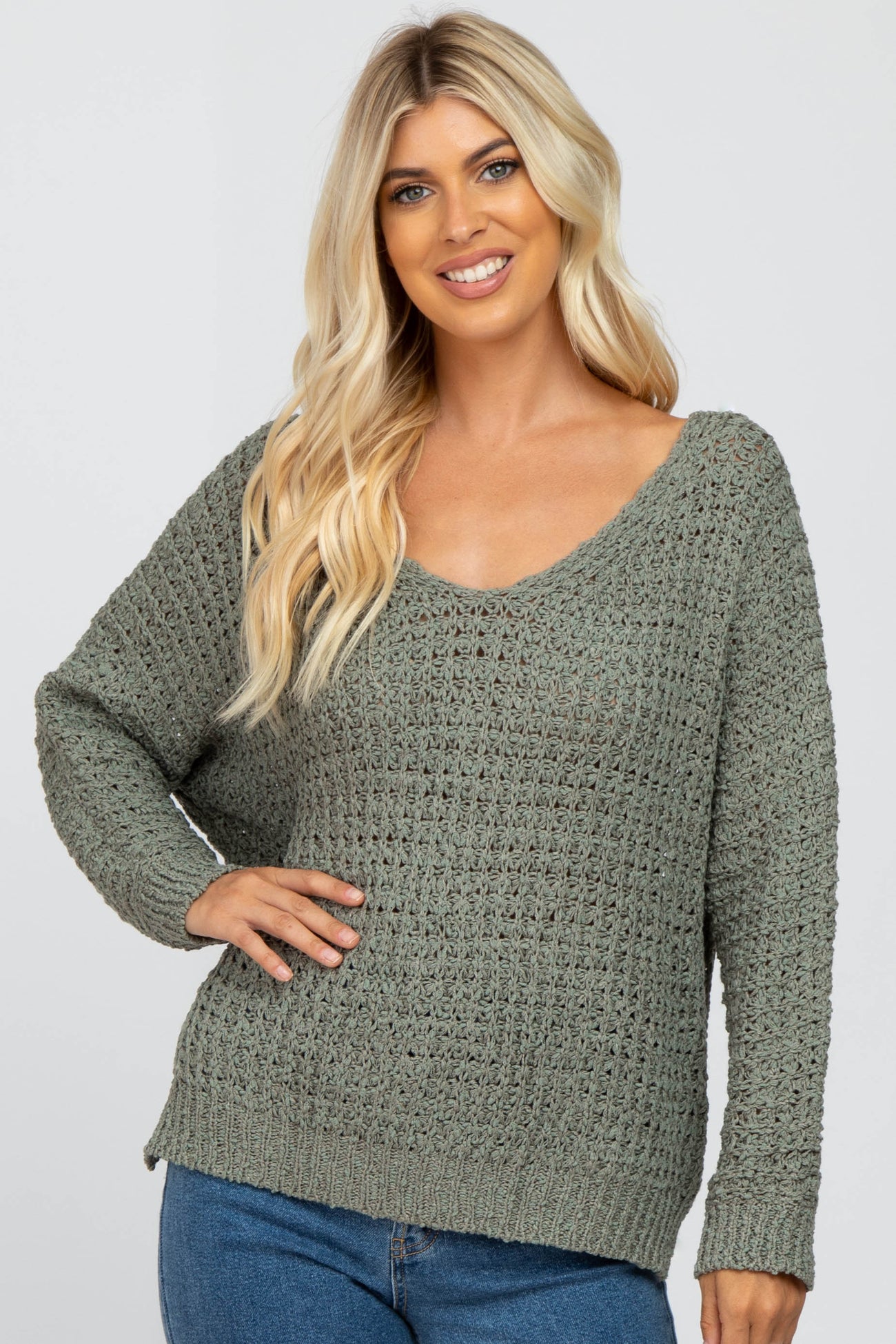woman wearing a loose-fitting olive green knit sweater with a v-neck and long sleeves