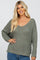 woman wearing a loose-fitting olive green knit sweater with a v-neck and long sleeves