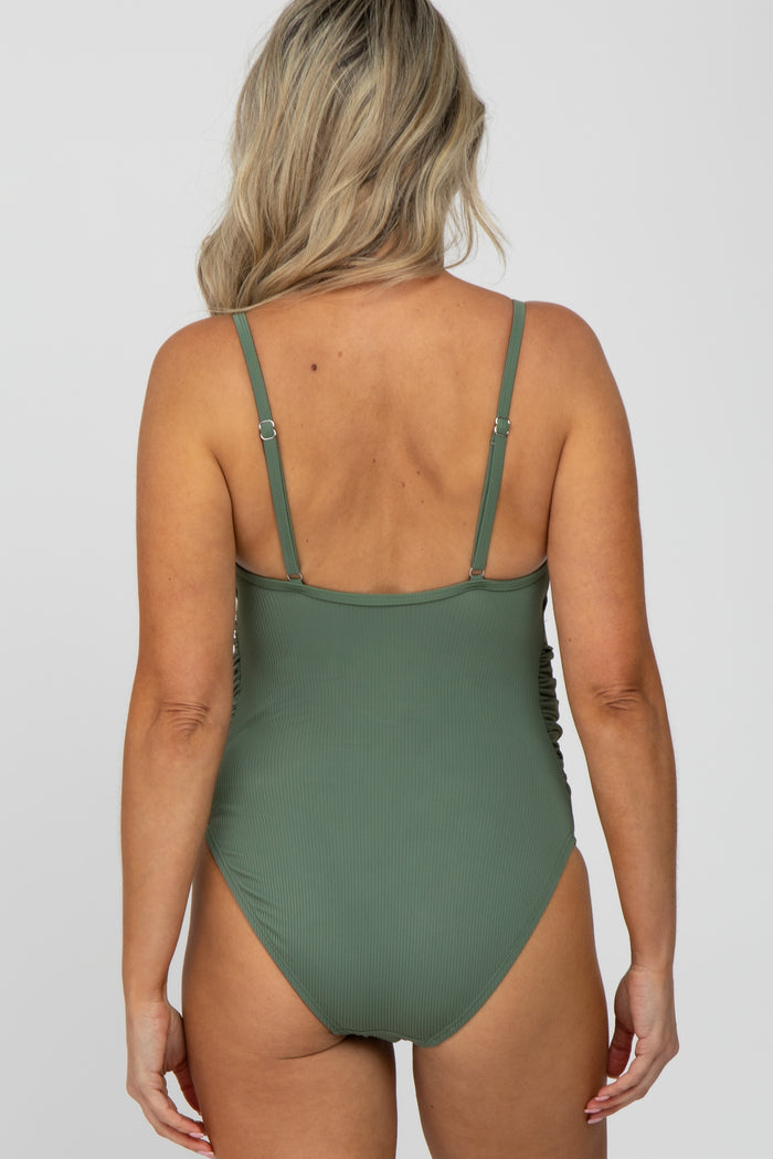 woman wearing a green maternity swimsuit with adjustable straps and a ribbed texture, showing the back view