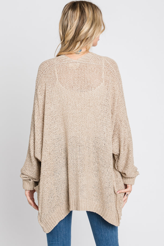 woman wearing a beige oversized knitted cardigan sweater with a loose fit and batwing sleeves