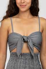 woman wearing a black and white gingham tie-front crop top with spaghetti straps