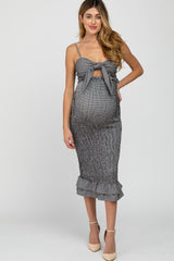woman wearing a black and white striped maternity dress with a tie-front and ruffle hem, showcasing her baby bump
