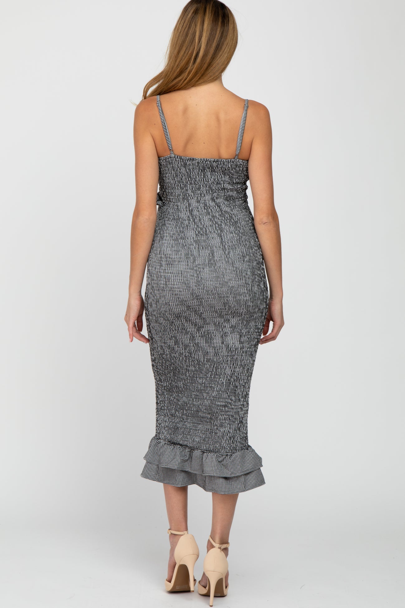 woman wearing a black and white striped maternity dress with a ruffled hem and adjustable straps