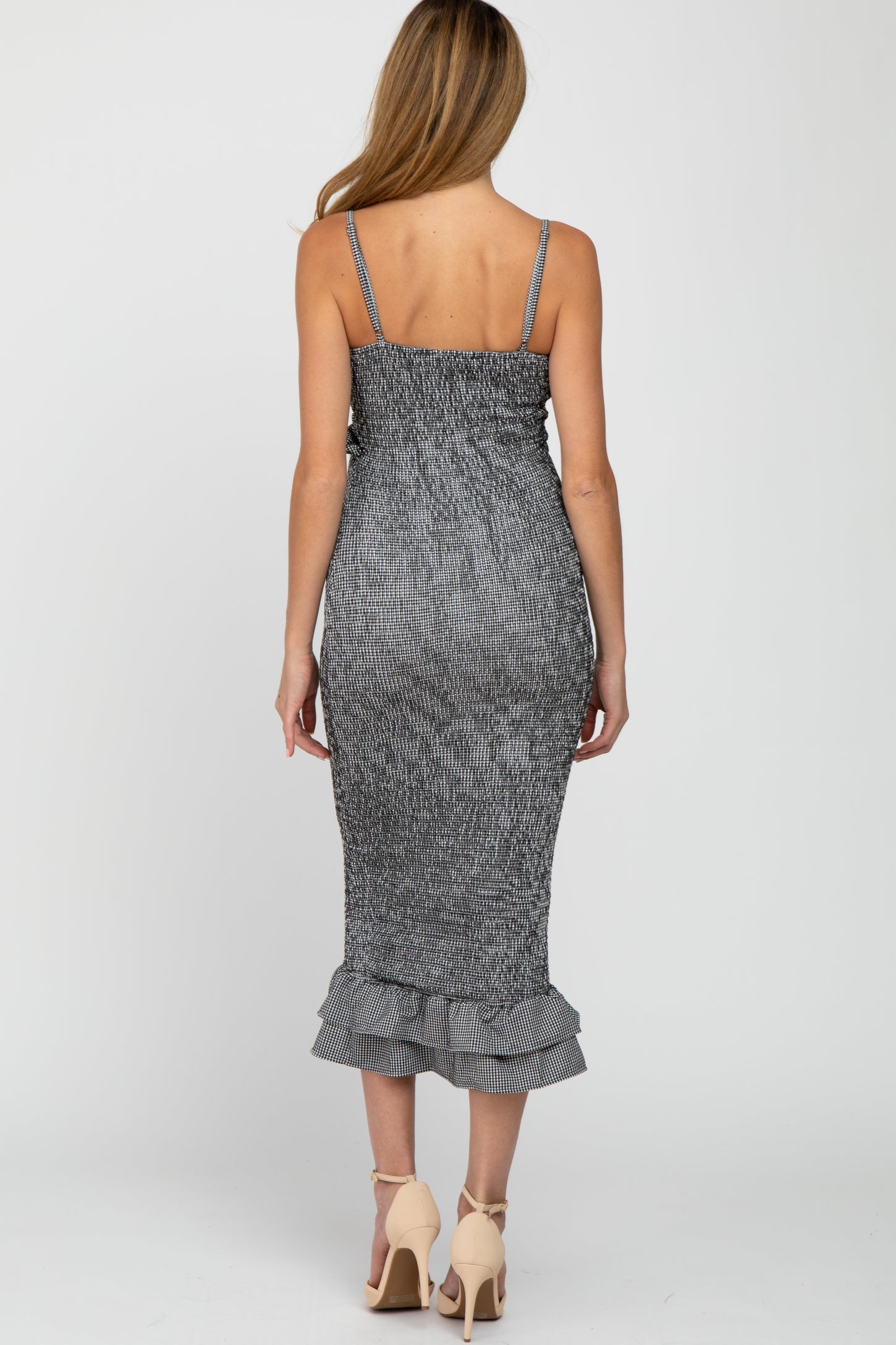 woman wearing a black and white striped maternity dress with a ruffled hem and adjustable straps