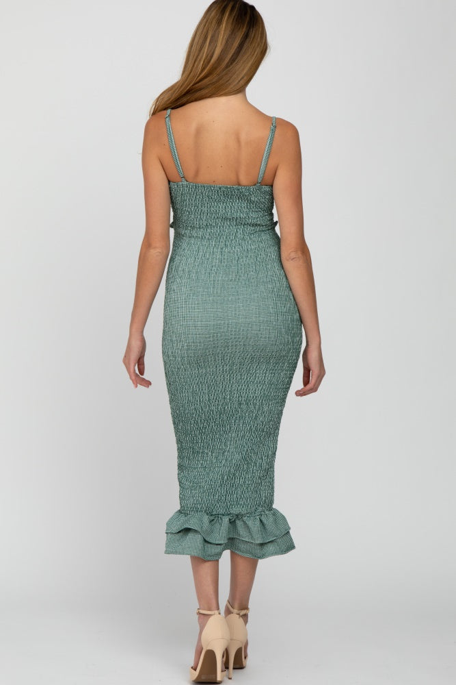 woman wearing a green smocked maternity dress with a ruffled hem and adjustable spaghetti straps, showing her back