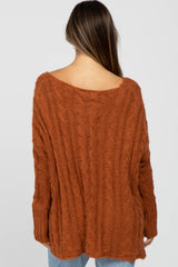 woman wearing an oversized rust-colored cable knit maternity sweater with an open back detail