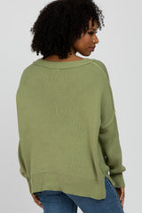 woman wearing a loose-fitting olive green sweater with a wide neckline and a relaxed fit, viewed from the back