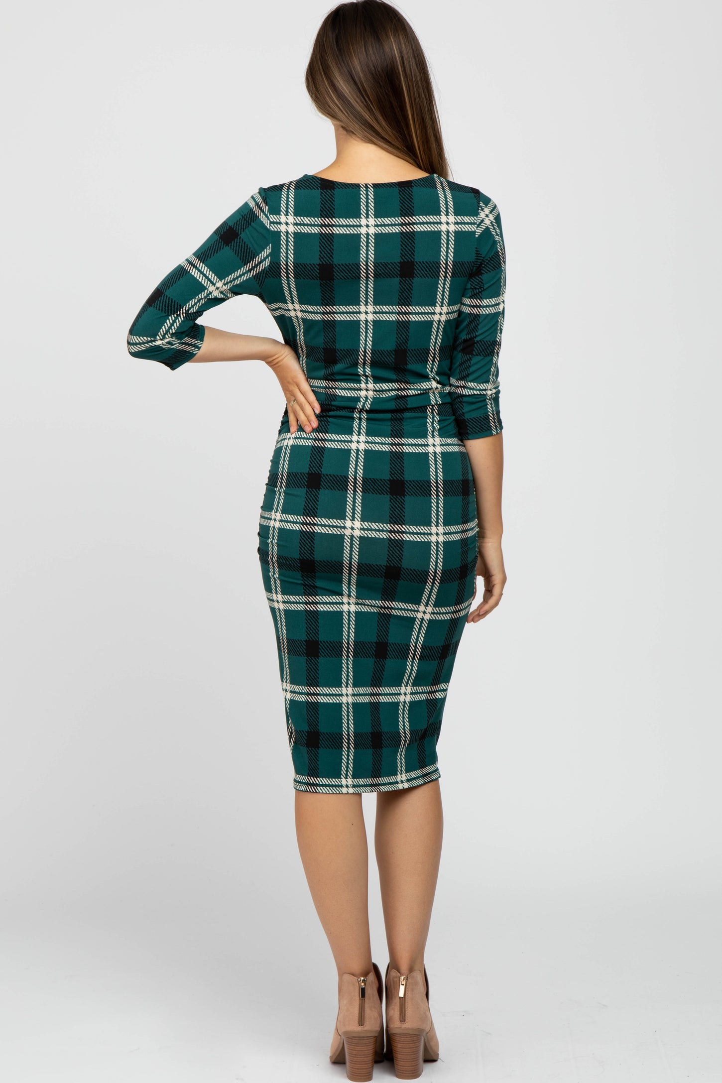 woman wearing a green and black plaid maternity dress with three-quarter sleeves and a fitted silhouette
