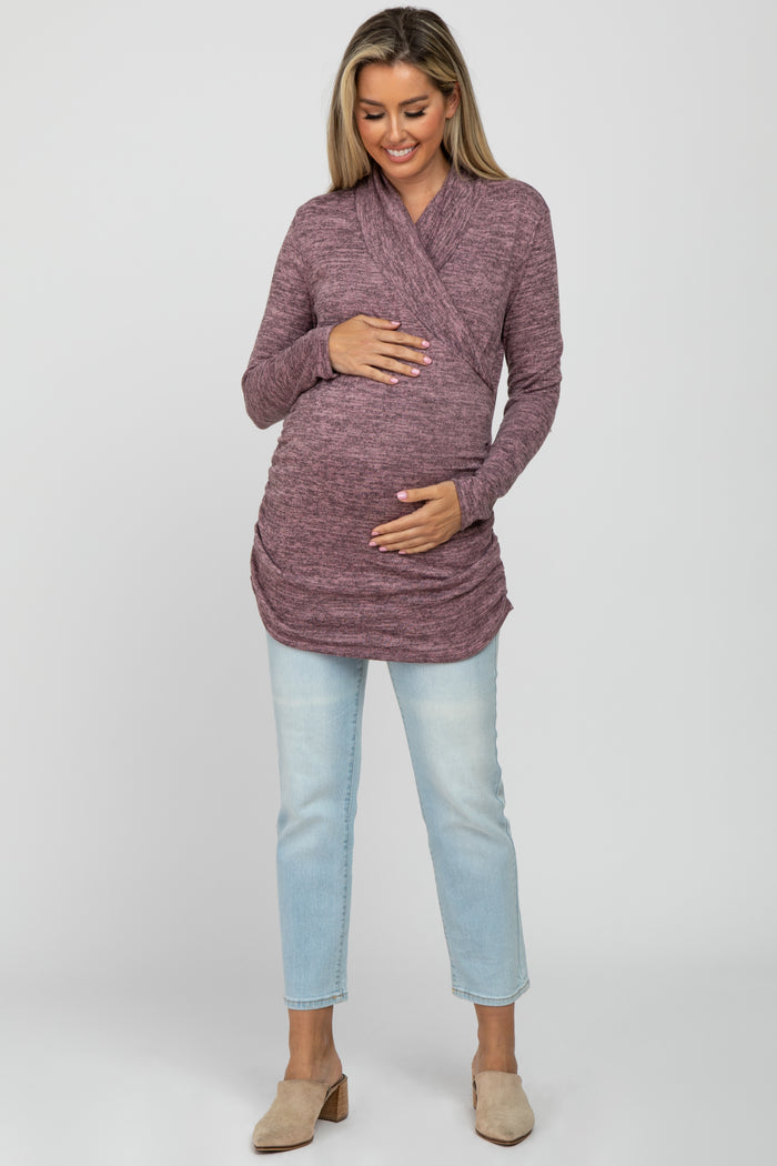 woman wearing a mauve long sleeve maternity top with a wrap design and holding her baby bump
