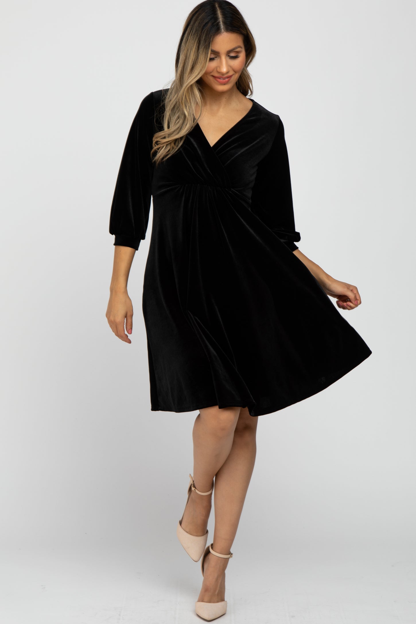 woman wearing a black velvet knee-length dress with three-quarter sleeves and a v-neckline