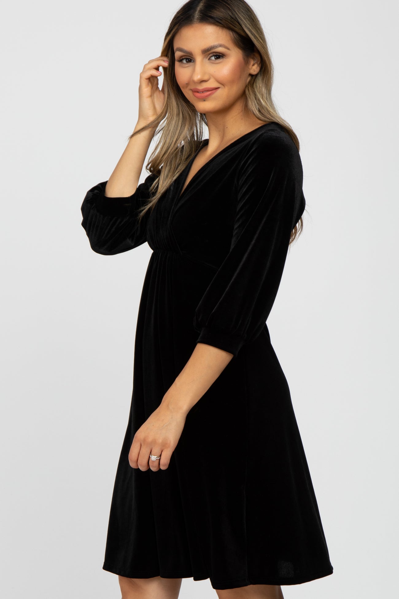 woman wearing a black velvet short sleeve dress with a v-neck and a flowy skirt