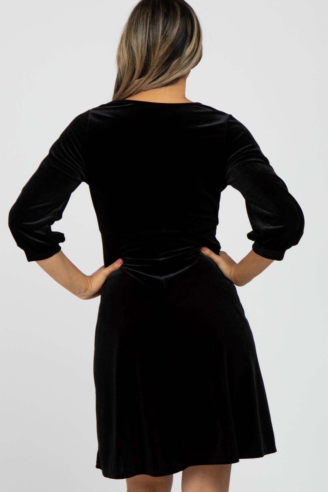 woman wearing a black velvet dress with three-quarter sleeves, showing the back view