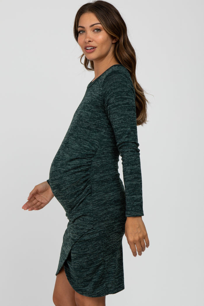 woman wearing a dark green long sleeve maternity dress with a side ruching detail and a visible baby bump