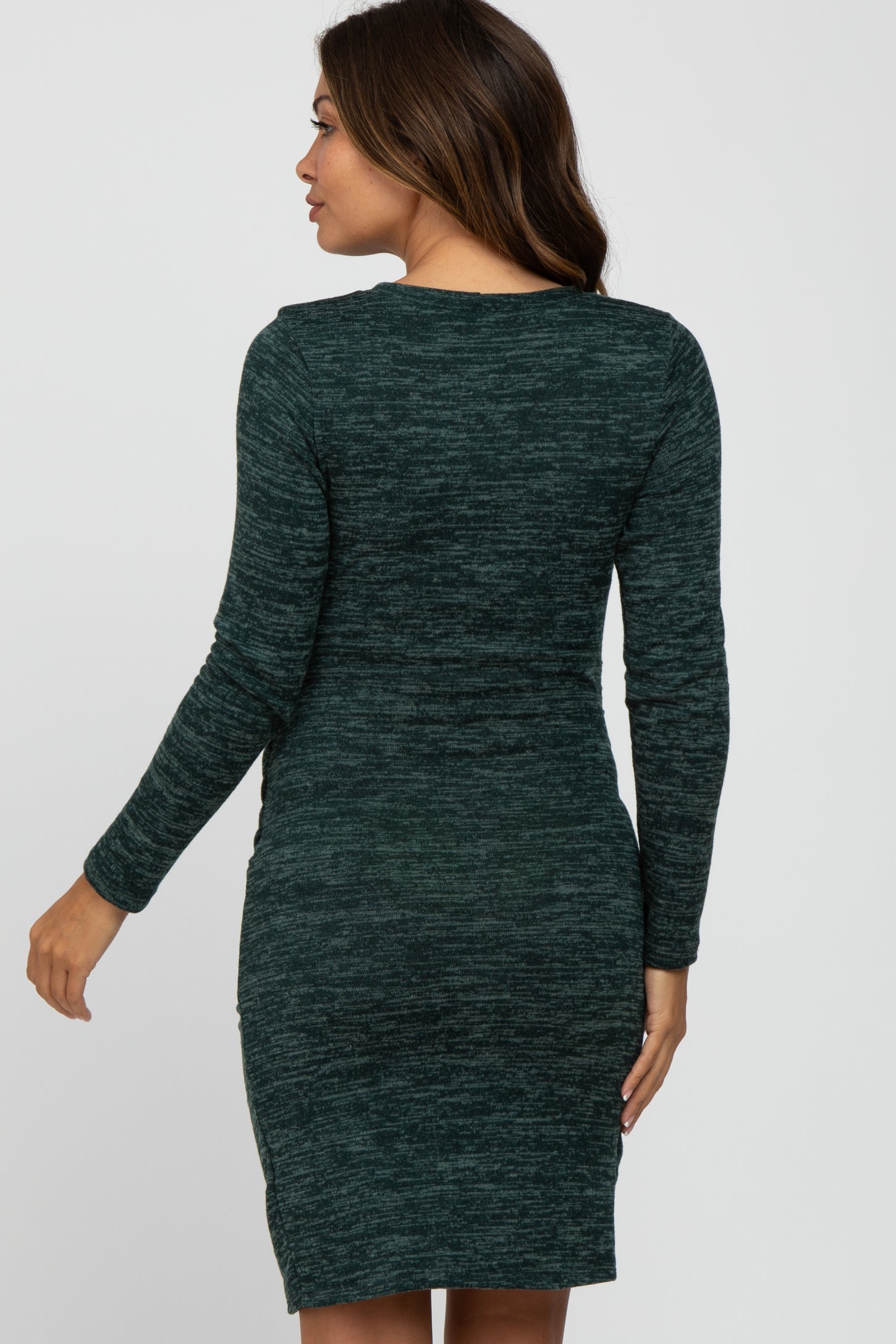 woman wearing a green long sleeve maternity dress with a fitted silhouette and side slit detail