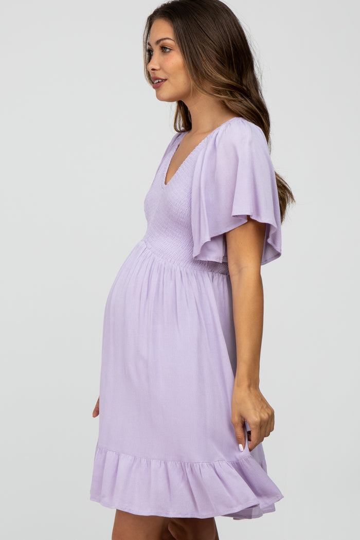 woman wearing a lavender maternity dress with a v-neck and flutter sleeves, highlighting her baby bump