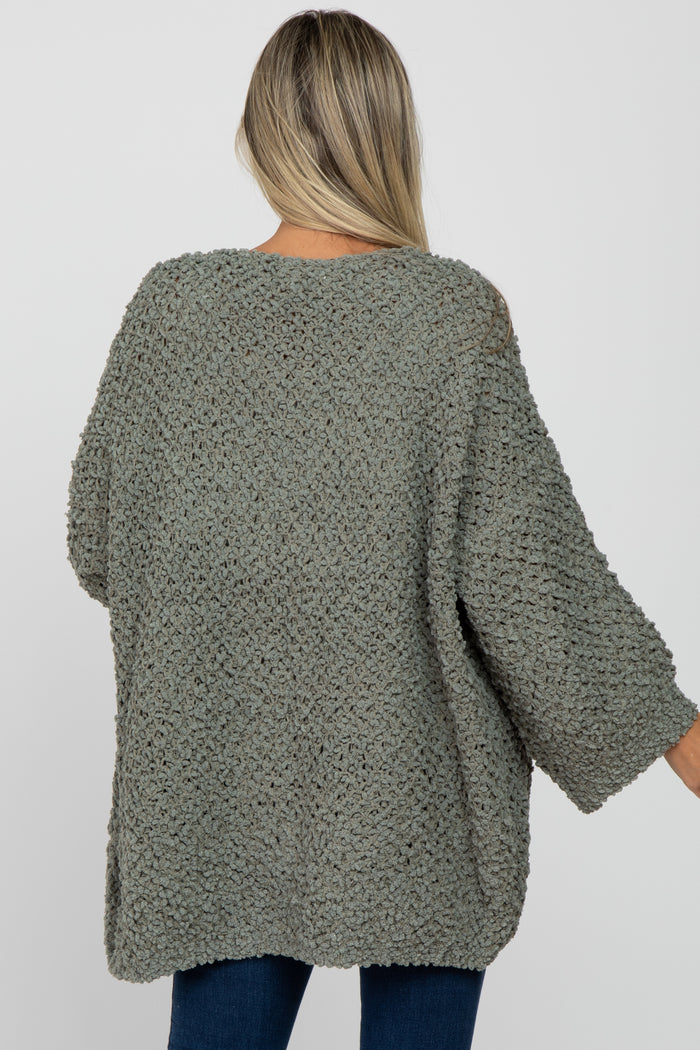 woman wearing a light green oversized maternity sweater with a cozy textured knit and three-quarter sleeves