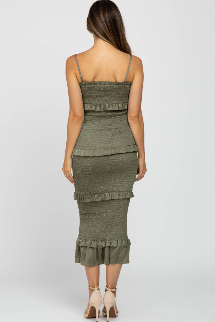 woman wearing a green maternity dress with ruffle details and a fitted silhouette, showing off a baby bump from behind