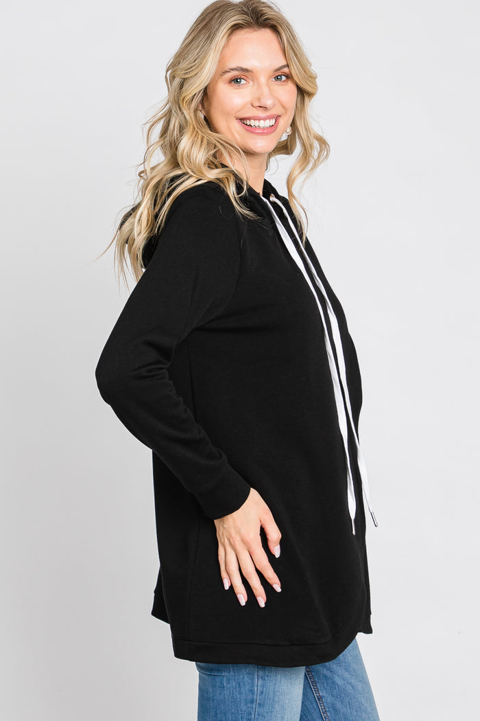 woman wearing a black long sleeve hoodie with white drawstrings and side slits, smiling and facing to the side