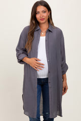 woman wearing a grey maternity button-up shirt over a white tank top and jeans, holding her baby bump