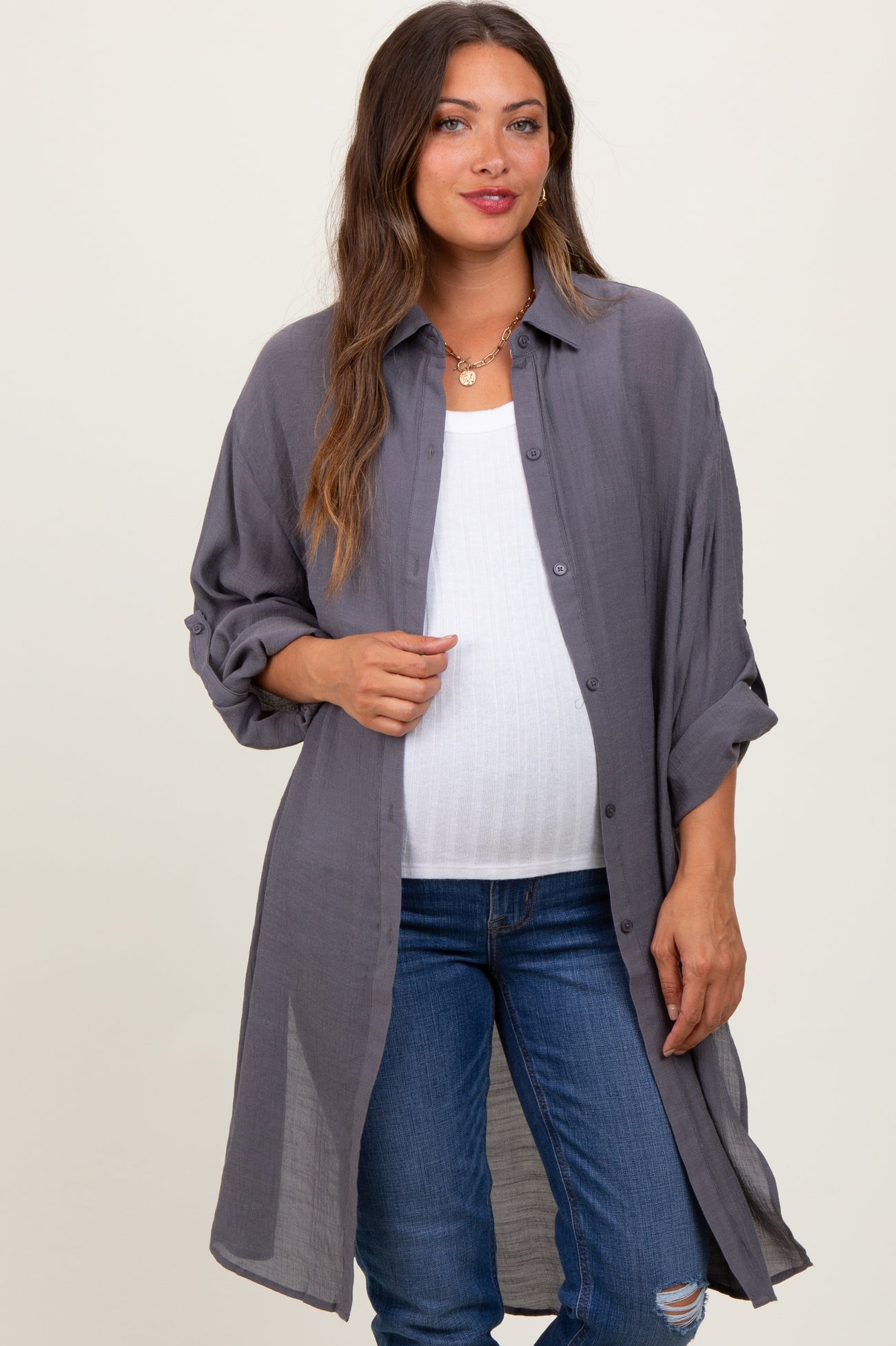 woman wearing a gray maternity button-up shirt over a white tank top and showing her baby bump with distressed jeans