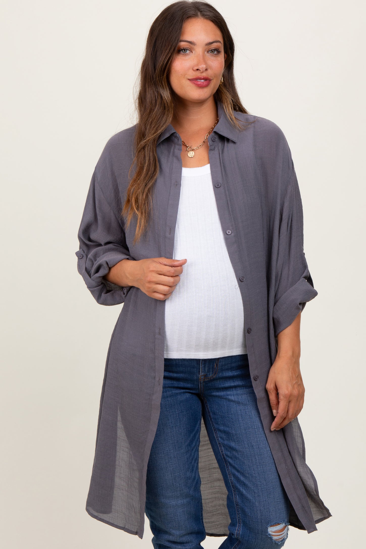 woman wearing a gray maternity button-up shirt over a white tank top and showing her baby bump with distressed jeans