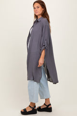 woman wearing a long gray button-up shirt with rolled sleeves, paired with light blue jeans and black sandals