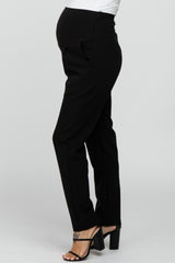 Side view of a pregnant person wearing black maternity dress pants and black high heel sandals