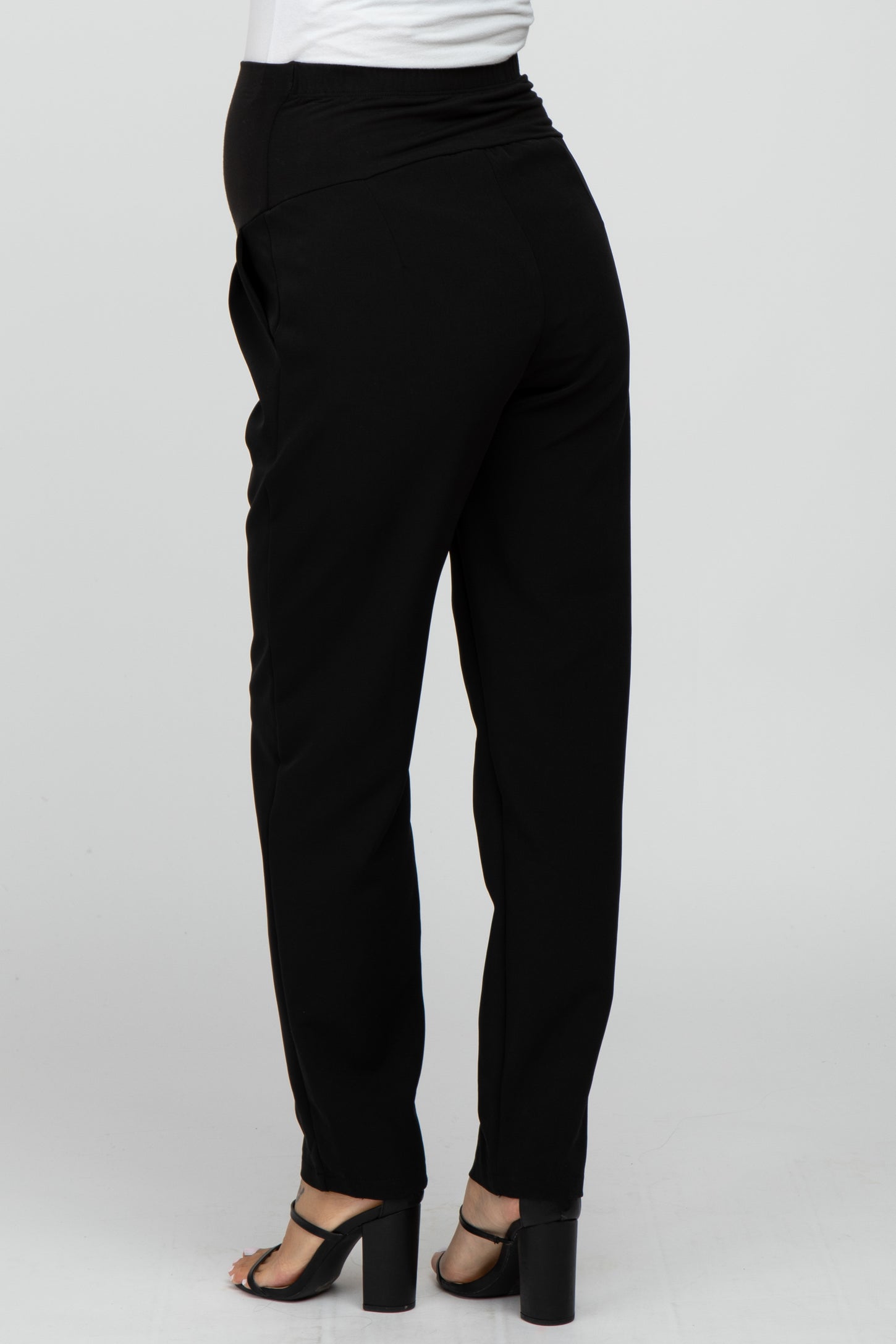 woman wearing black maternity pants, showing the back view and a visible baby bump