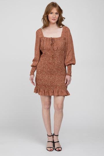 woman wearing a rust-colored floral print mini dress with puffed sleeves and a ruffled hem