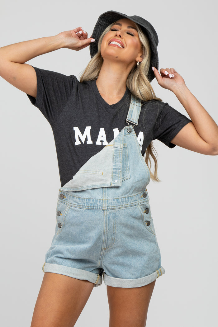 woman wearing a gray maternity t-shirt that says "mama" paired with denim overalls and a black bucket hat