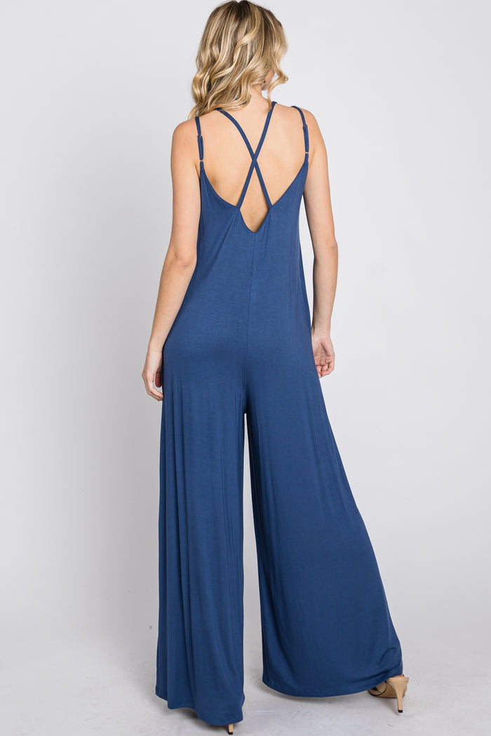 woman wearing a navy blue sleeveless jumpsuit with a crisscross back design and wide leg silhouette
