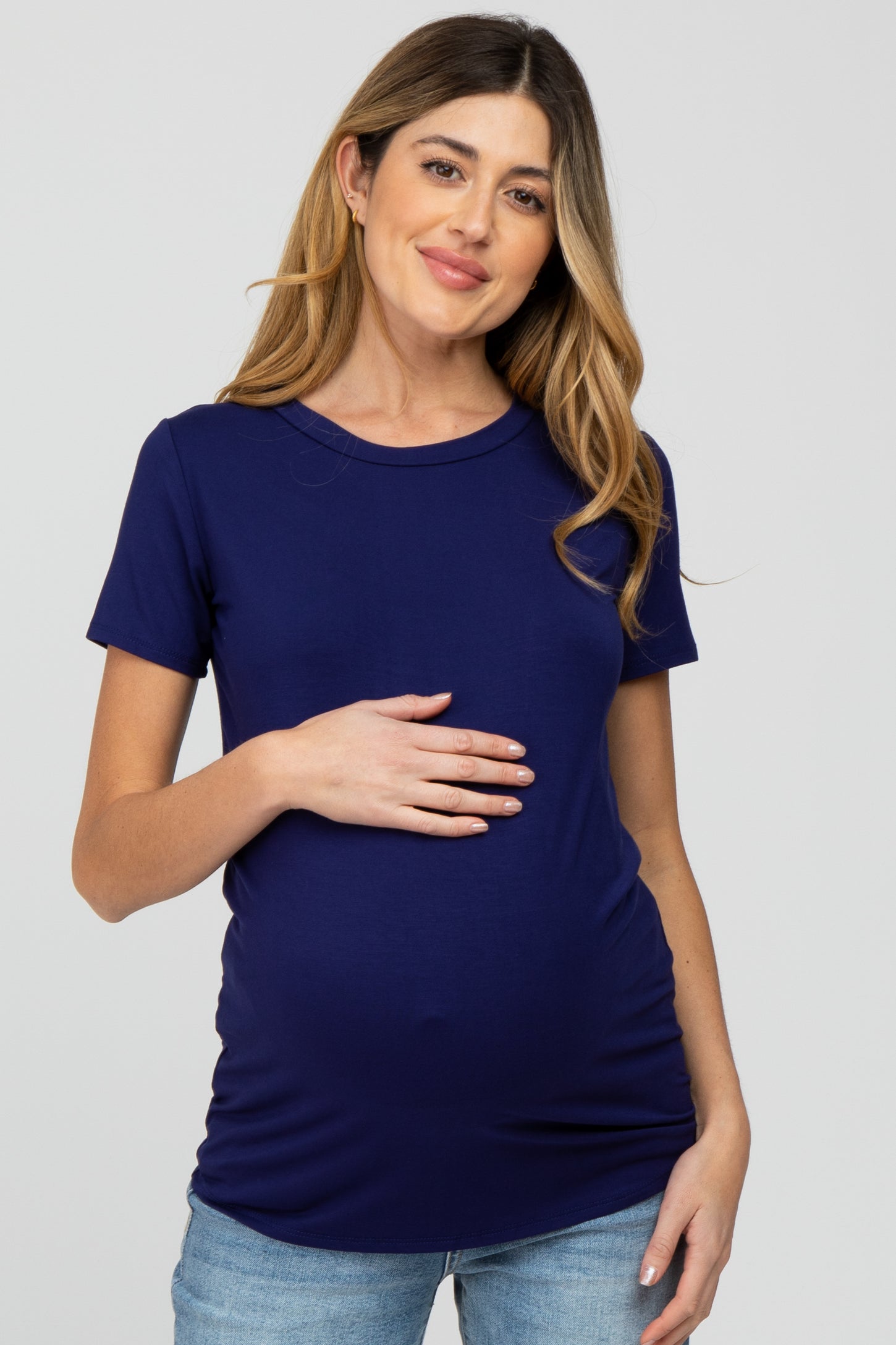 woman wearing a navy blue short sleeve maternity top and holding her baby bump