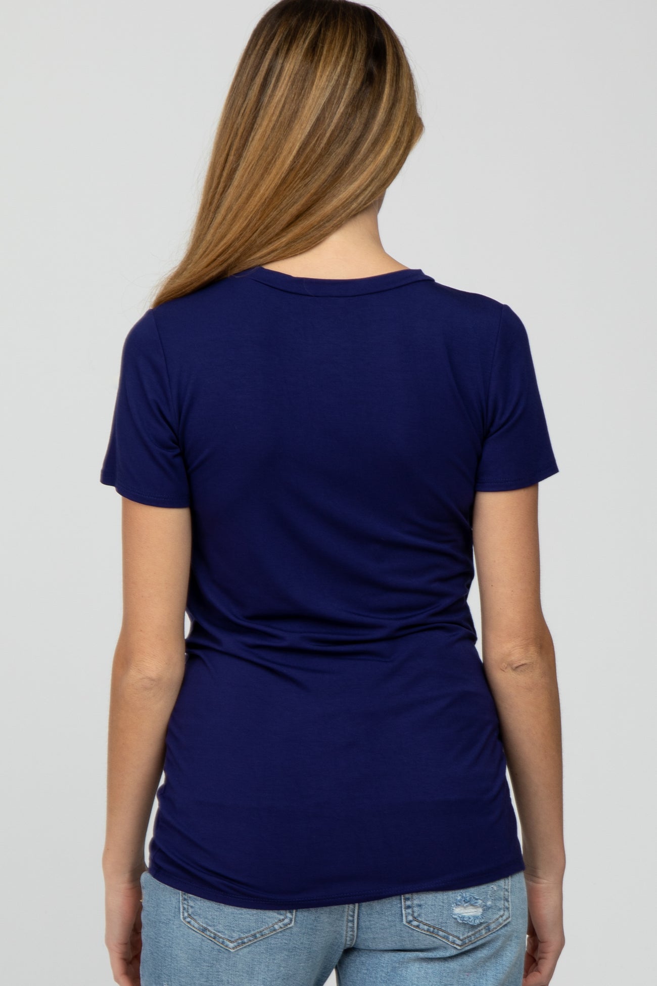 woman wearing a navy blue maternity t-shirt, showing the back view, paired with light blue jeans