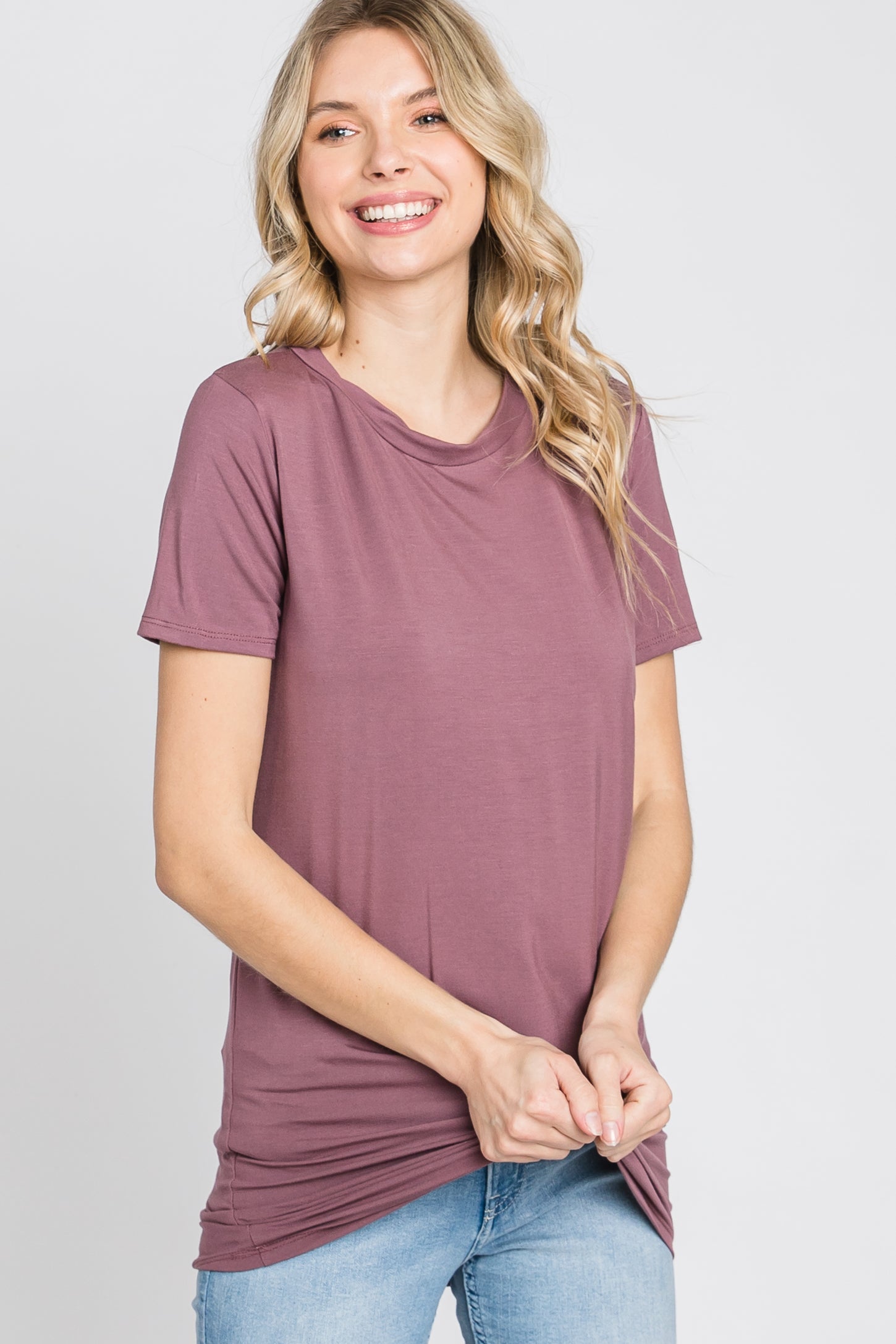 woman wearing a mauve short sleeve t-shirt with a relaxed fit and side ruching, smiling at the camera