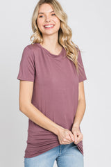 woman wearing a mauve short sleeve t-shirt with a relaxed fit and side ruching, smiling at the camera