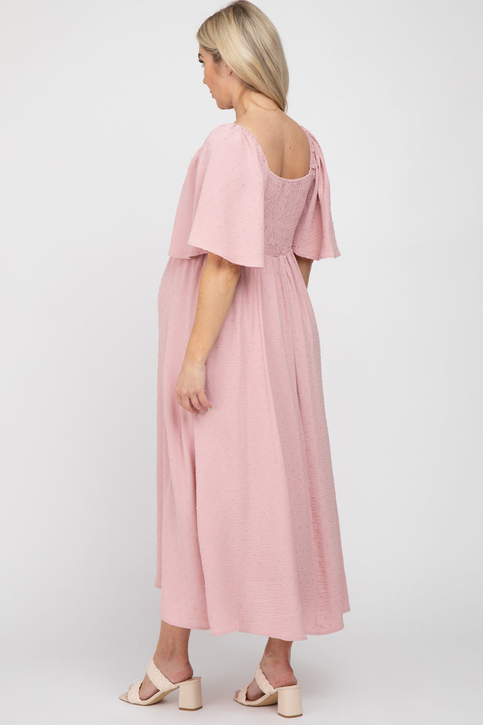 woman wearing a pink maternity dress with flutter sleeves and a loose fit, showing her baby bump from the back